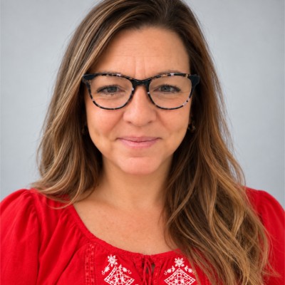 Abby Piatti, smiling in glasses and a red embroidered top